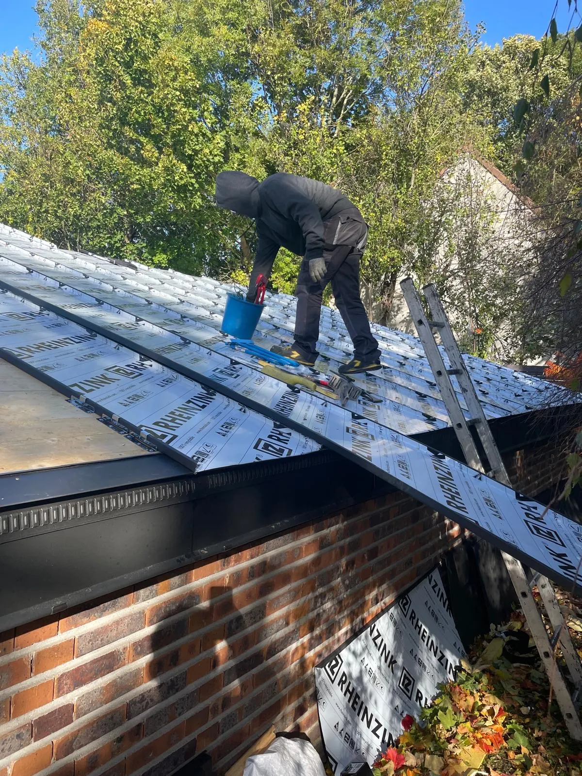 Couvreur façonnant une couverture en zinc sur un chantier
